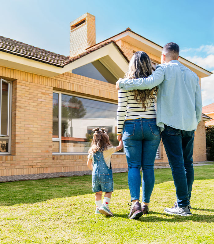 Rear view of a loving family walking in the back yard of their house